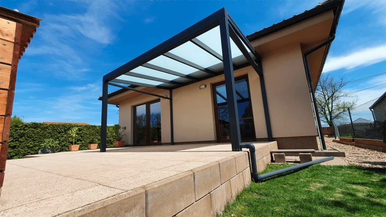 Moderne anthrazitfarbene Aluminium-Pergola mit verglastem Dach auf der Terrasse eines Einfamilienhauses