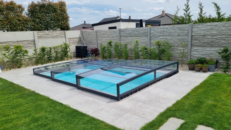 Moderne, niedrige Schwimmbadüberdachung mit anthrazitfarbener Konstruktion im Garten
