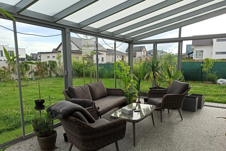 Moderne Verglasung von Balkon und Terrasse mit grauen Möbeln und Blick in den Garten