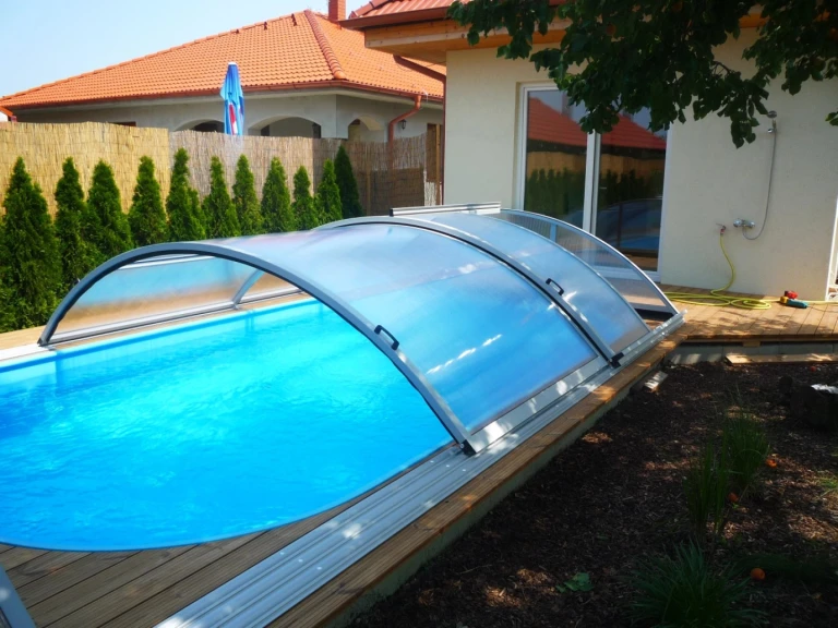 Halbrunde Schwimmbadüberdachung vom Typ KLASIK mit strahlend blauem Wasser im Garten eines Einfamilienhauses in Hrubý Šúr.