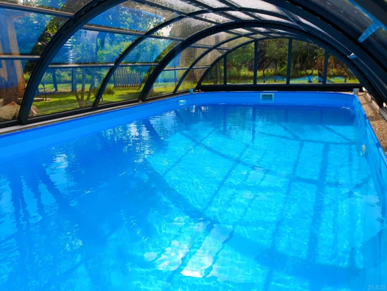 Blick auf das kristallklare blaue Wasser des Pools unter dem gewölbten Dach im Garten