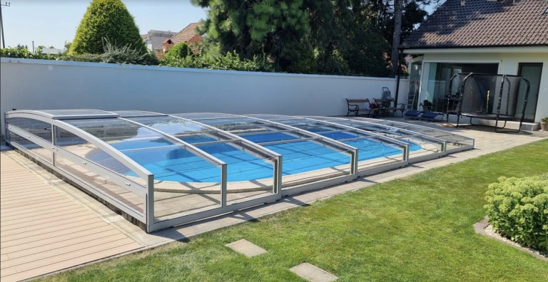 Moderne, niedrige Schwimmbadüberdachung mit transparenter Verkleidung im Garten eines Einfamilienhauses