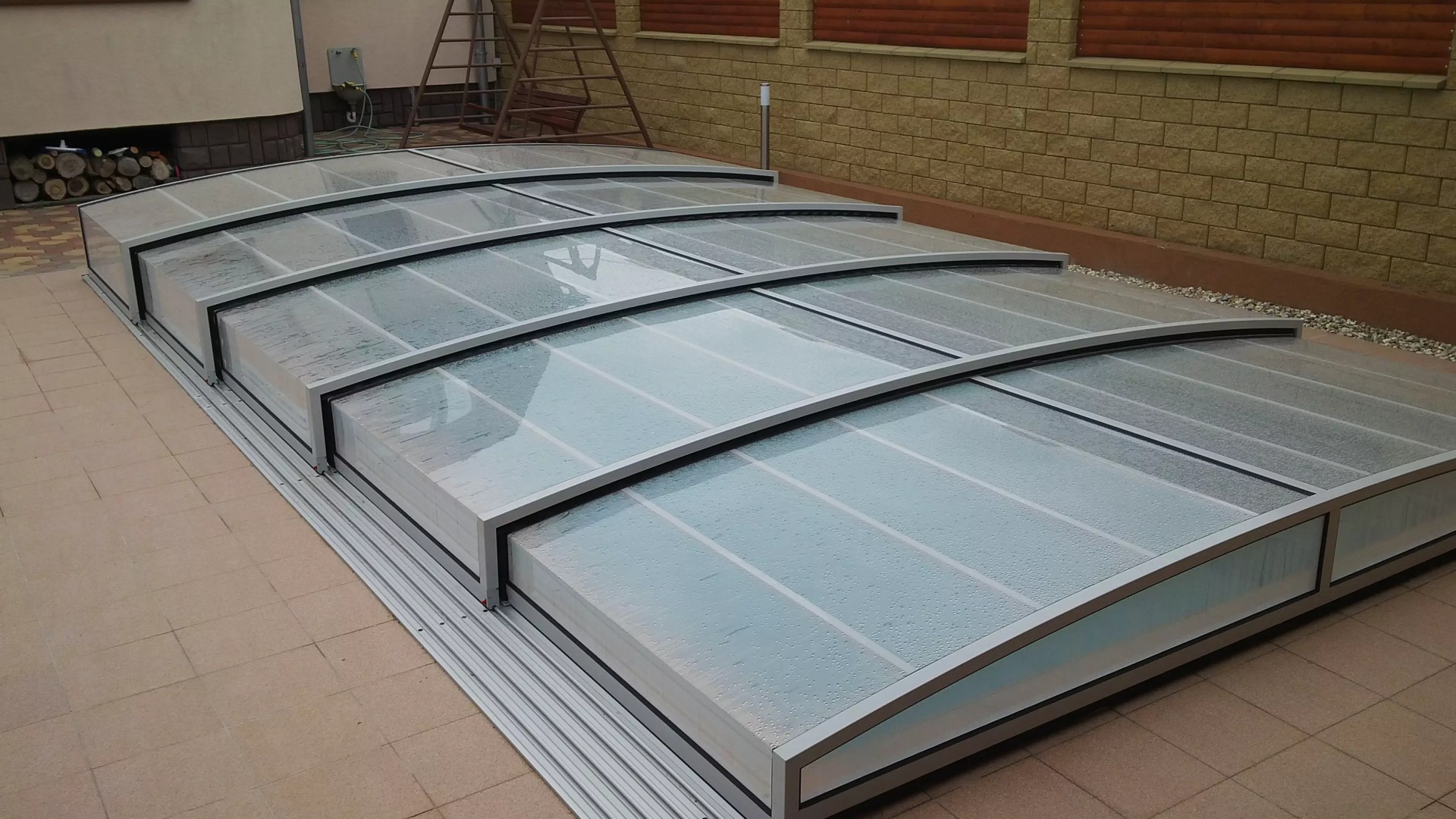 Moderne, niedrige Schwimmbadüberdachung mit Aluminiumkonstruktion und transparentem Füllmaterial.