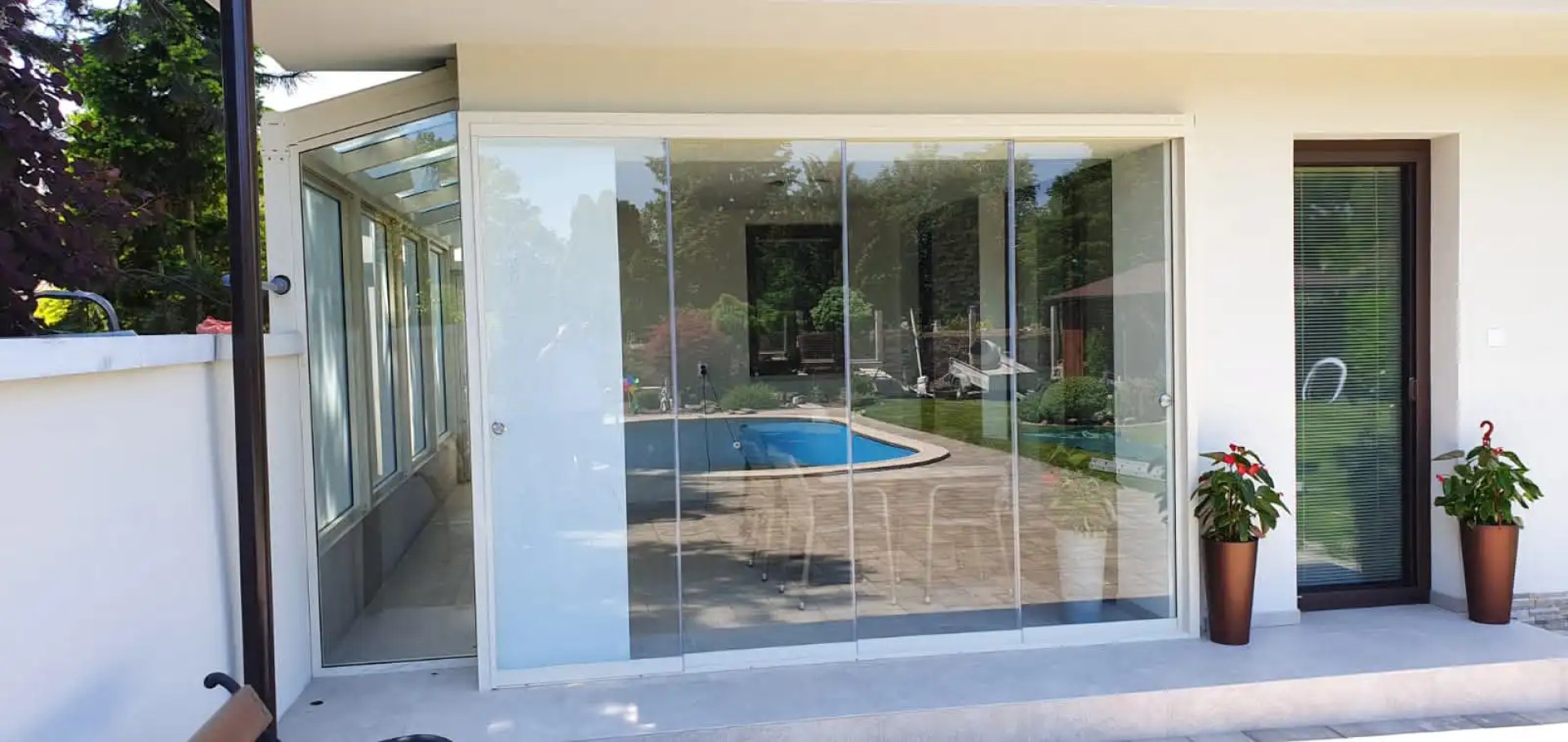 Moderne rahmenlose Terrassenverglasung an einem Einfamilienhaus mit Blick auf den Pool