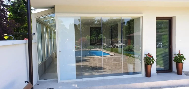 Moderne rahmenlose Terrassenverglasung an einem Einfamilienhaus mit Blick auf den Pool