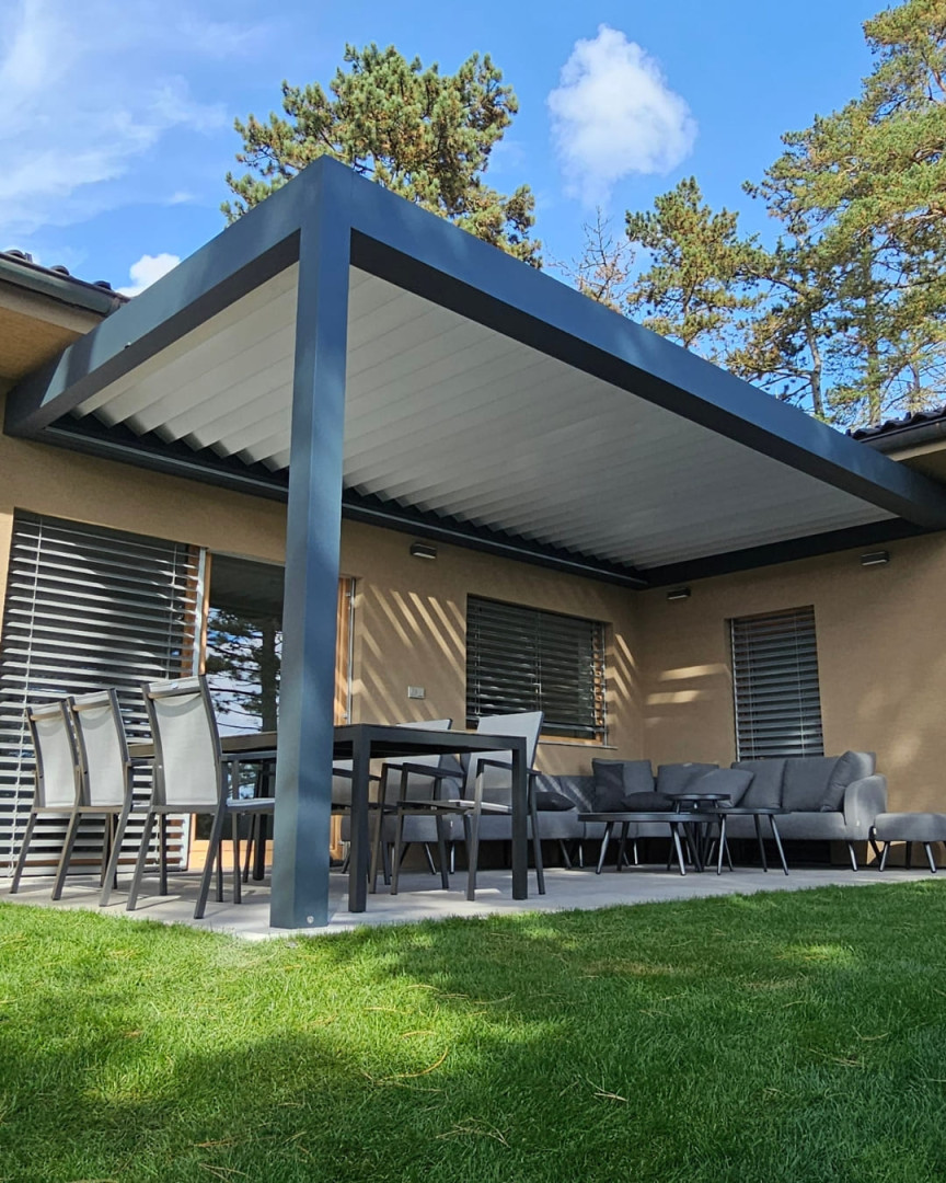 Eine moderne, bioklimatische Pergola mit Aluminiumkonstruktion und verstellbaren Lamellen auf der Terrasse eines Einfamilienhauses