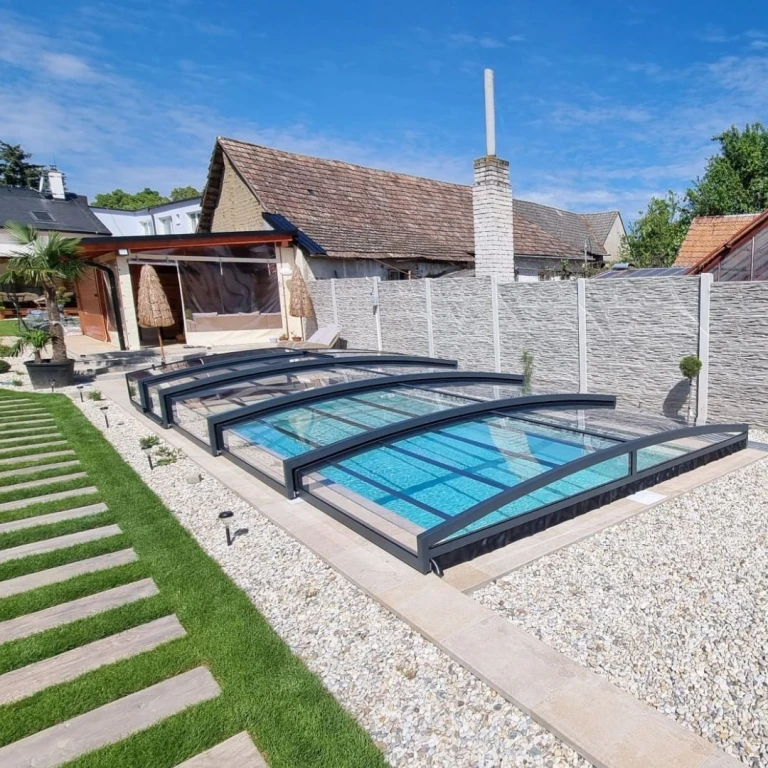 Ein moderner Pool im Garten mit einer stilvollen, niedrigen Überdachung in Anthrazit und einer gepflegten Umgebung.