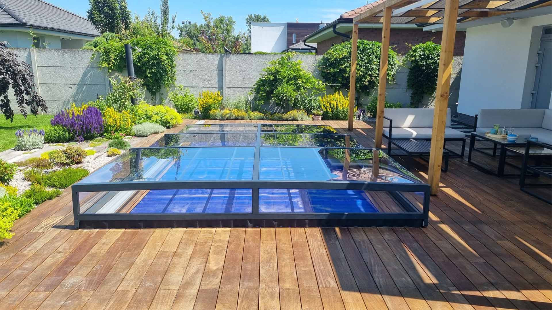 Moderne, niedrige, verglaste Schwimmbadüberdachung auf einer Holzterrasse im Garten