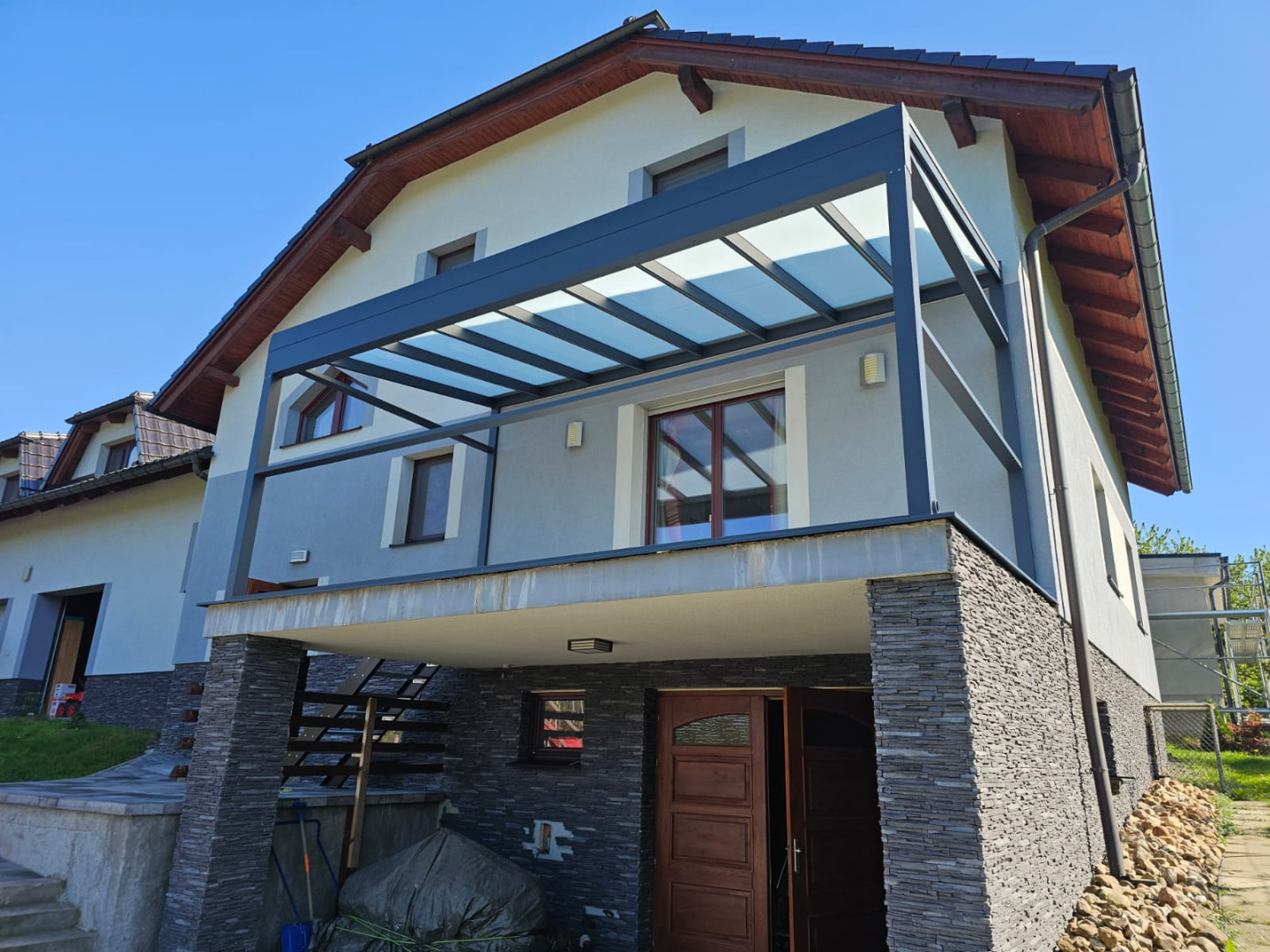 Eine moderne Aluminium-Pergola mit Glasdach, die auf dem Balkon eines Einfamilienhauses montiert ist