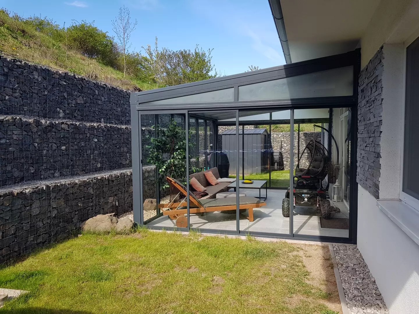 Eine moderne Aluminium-Pergola mit Glasüberdachung und Schiebesystem neben einem Haus in Braňany.