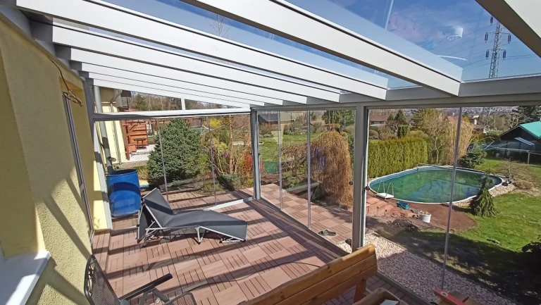 Eine moderne, verglaste Aluminium-Pergola mit Terrasse und Blick auf den Garten mit Swimmingpool