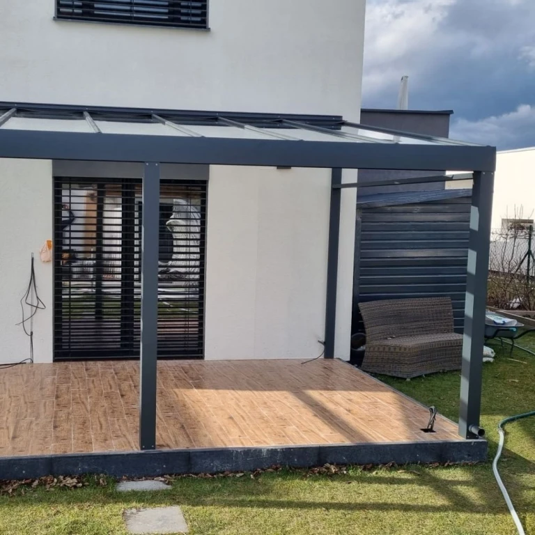 Eine moderne Wintergartenkonstruktion aus Aluminium in Anthrazit auf einer Terrasse mit Holzboden.