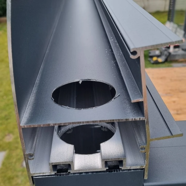 Detailansicht eines Schnitts durch ein Aluminiumprofil einer Regenrinne mit einer gebohrten Öffnung für den Schornstein.