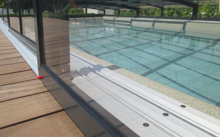 Ein detaillierter Blick auf die Schiene und die Konstruktion der niedrigen Überdachung des Pools auf der Holzterrasse.