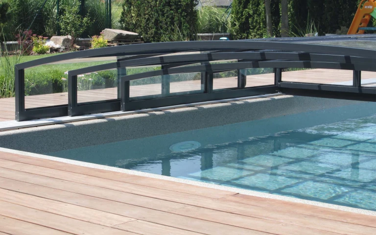 Detailansicht der niedrigen Aluminium-Überdachung des Schwimmbeckens mit Schienen auf der Holzterrasse