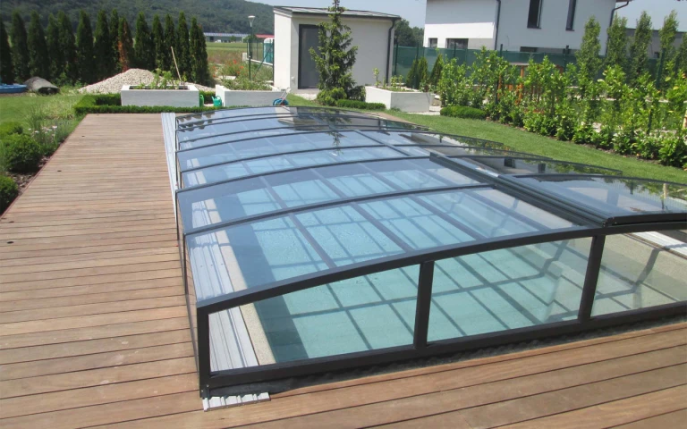 Moderne, niedrige Aluminium-Poolüberdachung in dunkler Farbe auf einer Holzterrasse