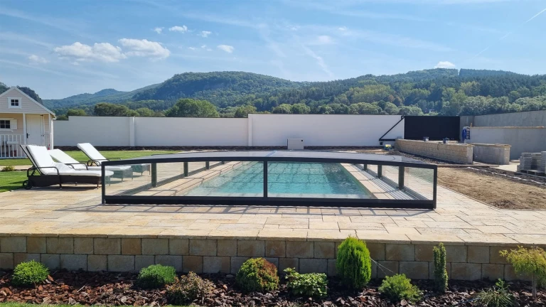 Moderne, niedrige Aluminium-Schwimmbadüberdachung auf der Terrasse mit Blick auf die Berge