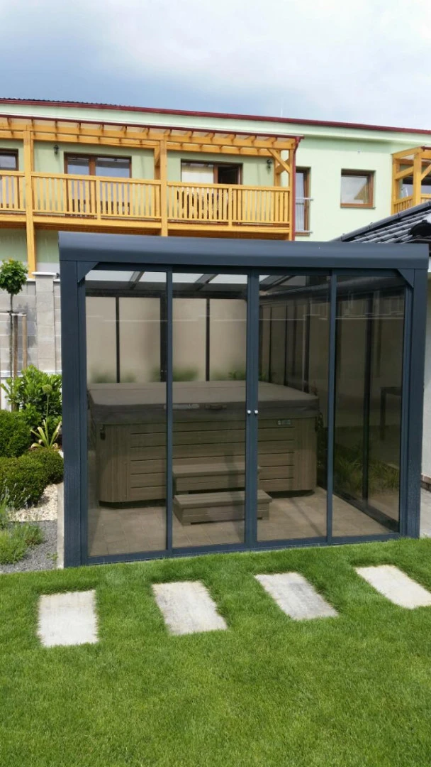 Ein moderner, verglaster Unterstand mit Whirlpool im Garten eines Einfamilienhauses.