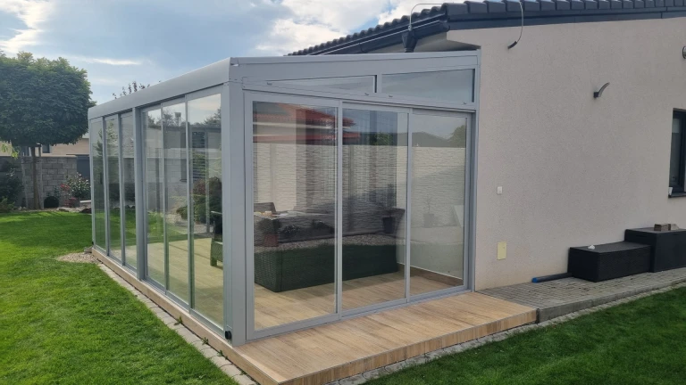 Ein moderner, verglaster Wintergarten mit Aluminiumkonstruktion, der an ein Einfamilienhaus angebaut wurde