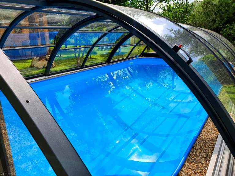 Ein Detailblick auf den blauen Pool mit der eingebauten Bogenüberdachung im Garten.