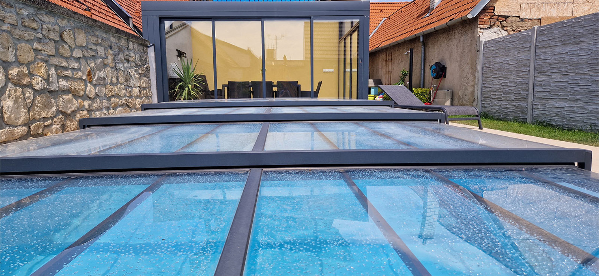 Ein detaillierter Blick auf die niedrige Aluminium-Schwimmbadüberdachung mit modernem grauen Rahmen im Garten.