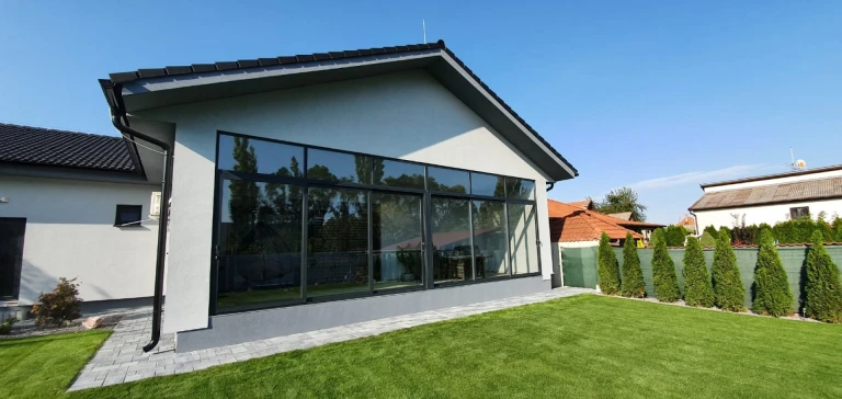 Moderne Terrassenverglasung eines Einfamilienhauses mit grauen Profilen und Blick in den Garten