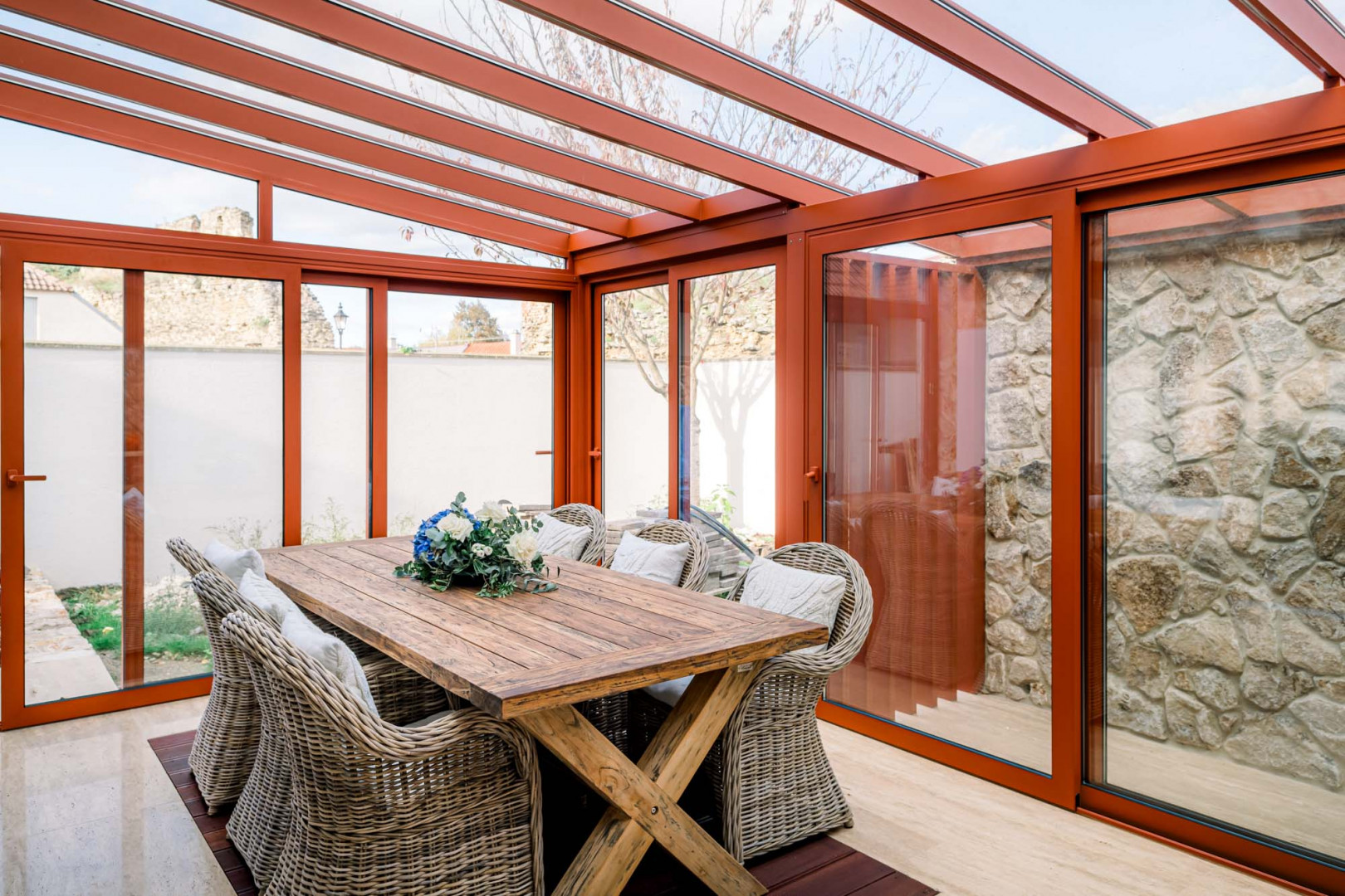 Ein moderner Wintergarten mit einem Holztisch und Rattanstühlen