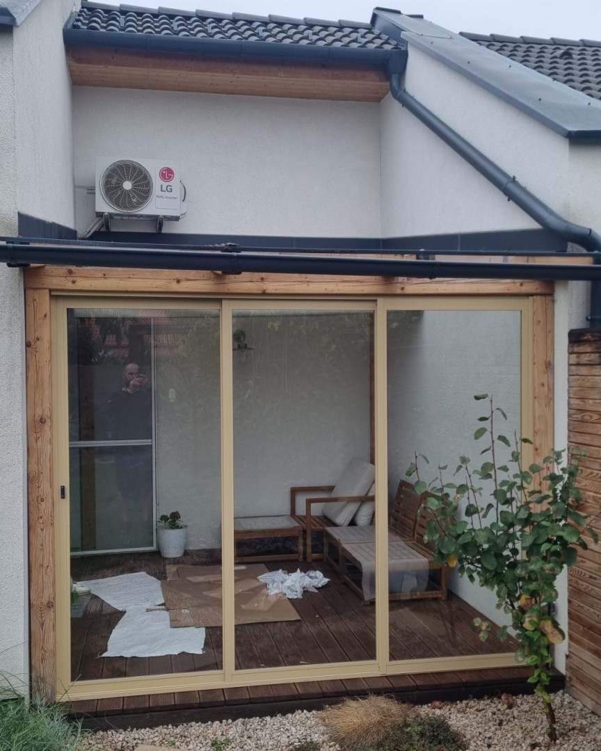 Moderne verglaste Schiebetüren auf der Terrasse mit Holzrahmen und Gartenmöbeln.