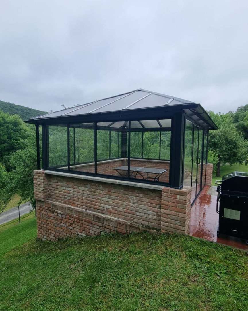 Ein moderner, verglaster Pavillon mit Ziegelfundament im Garten