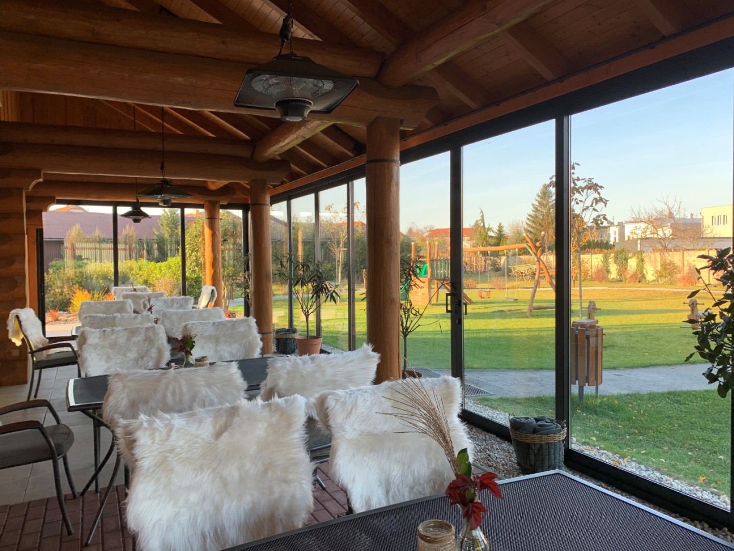 Verglaste Terrasse des Blockhauses mit Blick auf den Garten und den Kinderspielplatz