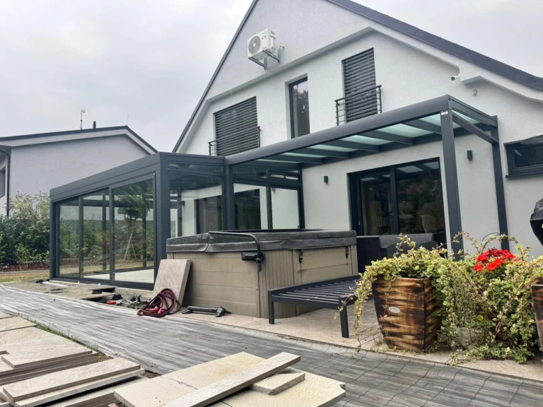 Ein moderner verglaster Anbau an ein Einfamilienhaus mit Whirlpool auf der Terrasse während der Montage.
